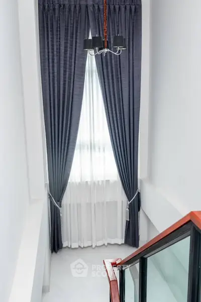 Bright and airy corner unit with high ceilings, elegant dark curtains, and a chic chandelier, perfect for a modern living space.