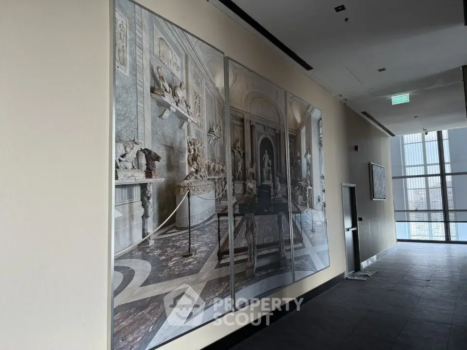 Elegant corridor with artistic wall decor and large windows offering natural light.