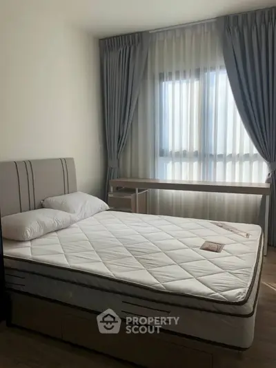 Modern bedroom with large window and elegant curtains, featuring a comfortable bed and stylish decor.