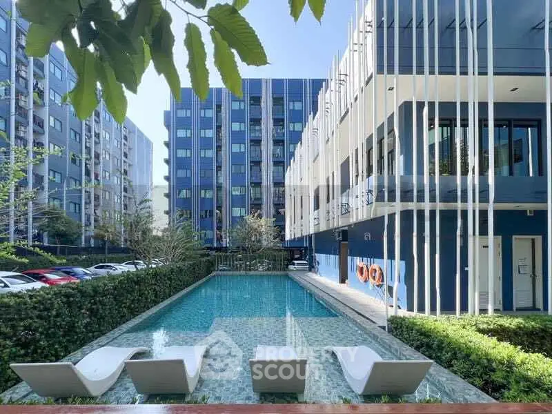 Modern apartment complex with sleek pool and stylish lounge chairs, perfect for urban living.
