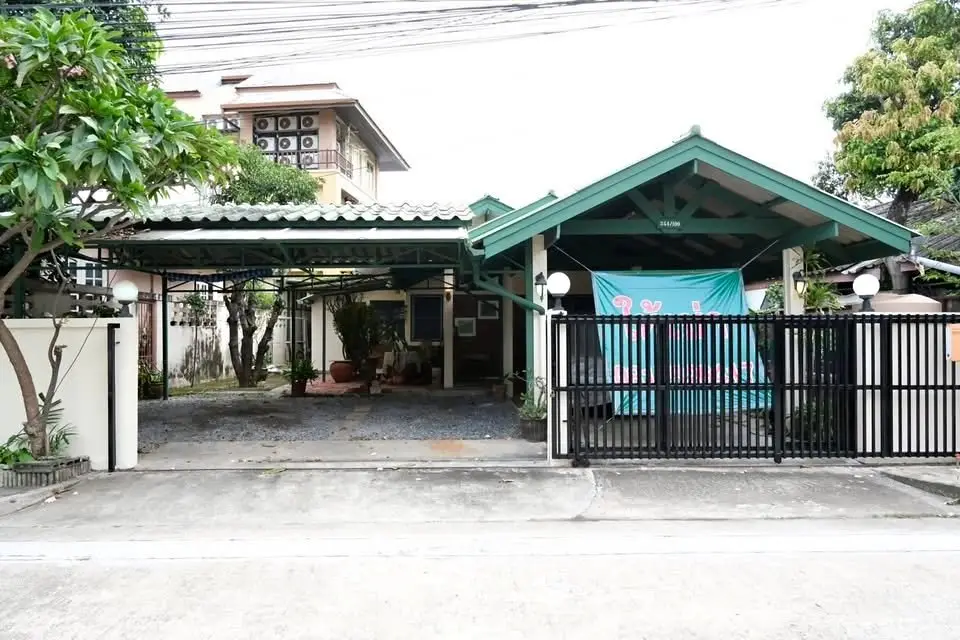 Charming suburban home with carport and gated entrance, surrounded by lush greenery.