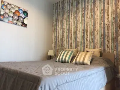 Cozy bedroom with stylish striped wallpaper and comfortable bedding, perfect for relaxation.