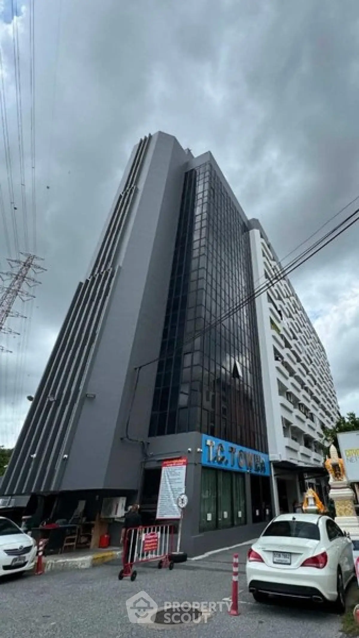 Modern high-rise building with sleek design and glass facade under cloudy sky.