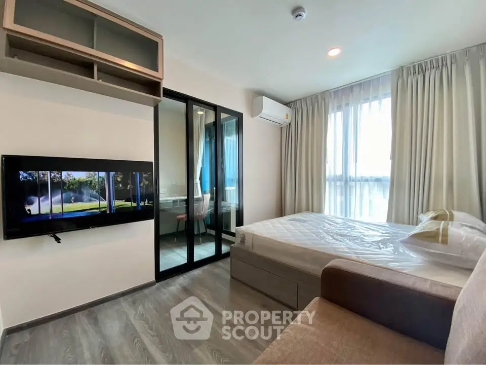 Modern bedroom with large window and wall-mounted TV in stylish apartment
