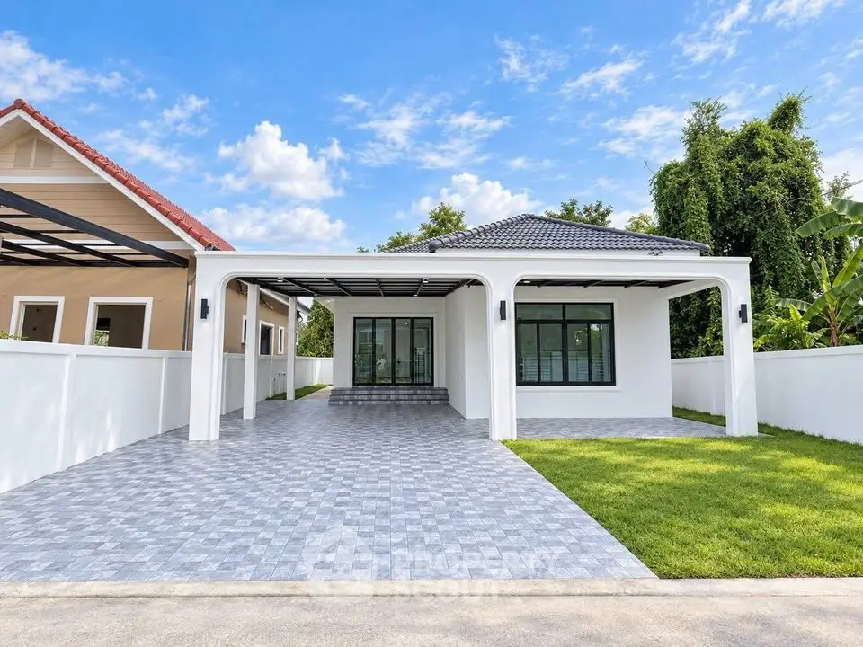 Modern single-story house with spacious driveway and lush green lawn under a clear blue sky.