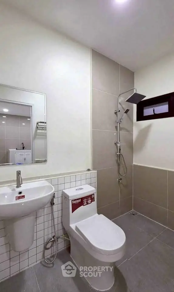 Modern bathroom with sleek fixtures and neutral tiles, featuring a rain shower and contemporary design.