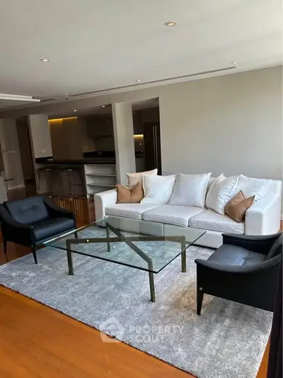 Spacious living room with modern furniture and glass coffee table in a stylish apartment.