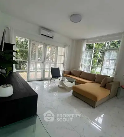 Spacious living room with large windows and modern furniture, offering a bright and airy atmosphere.