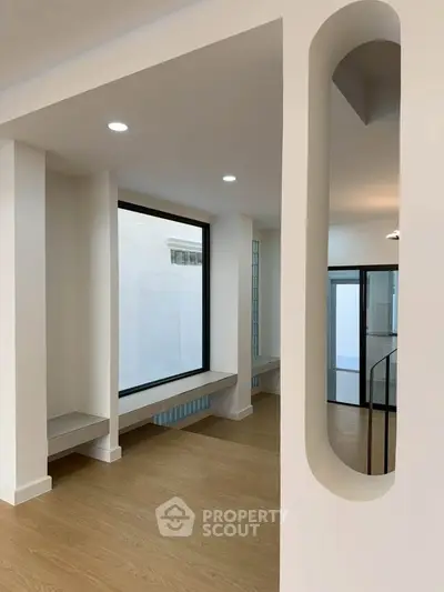 Modern minimalist interior with large windows and wooden flooring, perfect for contemporary living.