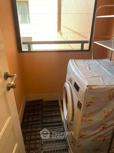 Compact laundry area with washing machine and storage rack in cozy apartment.