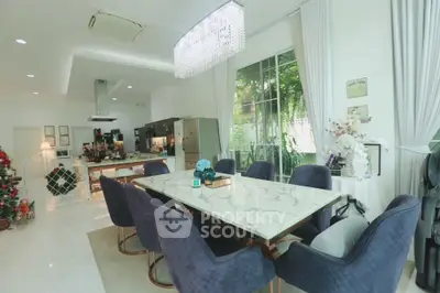 Luxurious dining area with elegant marble table, plush navy chairs, and modern kitchen in open layout design.