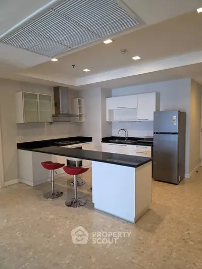 Modern kitchen with sleek white cabinets, black countertops, and stainless steel appliances.