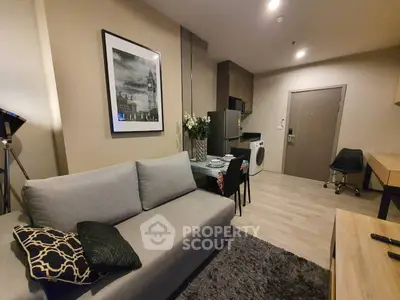 Modern living room with cozy sofa, stylish decor, and compact kitchen area featuring washing machine.