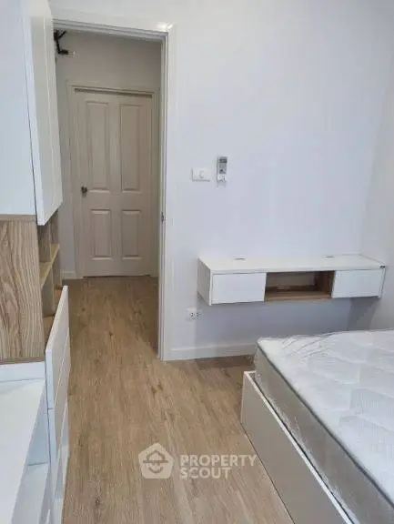 Modern minimalist bedroom with wooden flooring and built-in storage