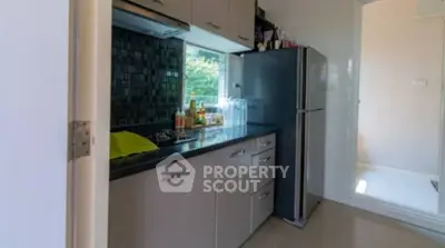 Modern kitchen with sleek cabinetry and large fridge, featuring a window view.