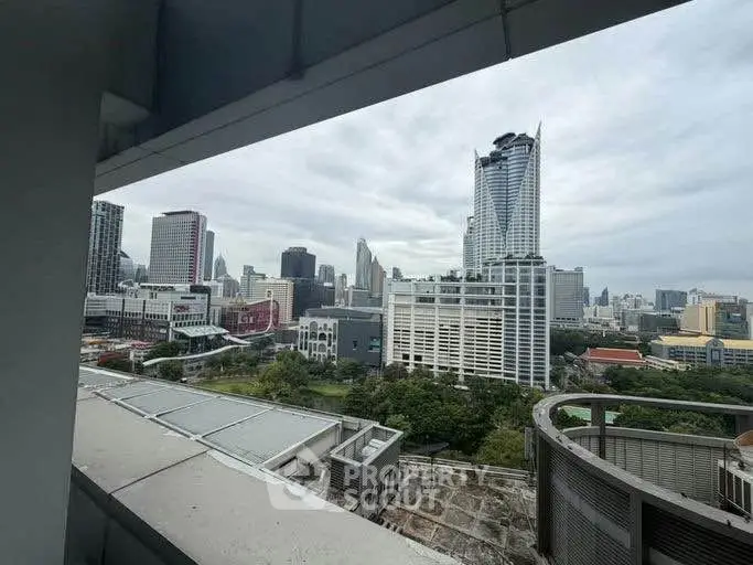 Stunning cityscape view from a high-rise balcony overlooking modern skyscrapers and lush greenery.
