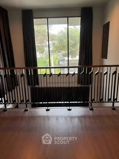 Elegant interior with large window and modern railing, offering a serene view.