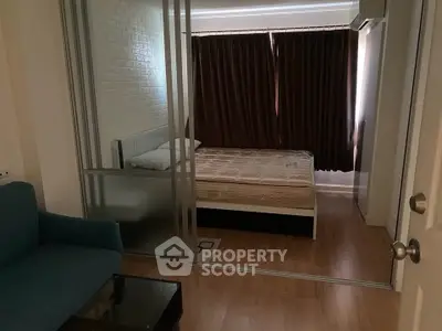 Cozy bedroom with sliding glass doors and wooden flooring in modern apartment.