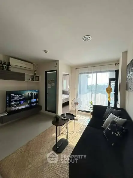 Modern living room with natural light, cozy seating, and entertainment setup.