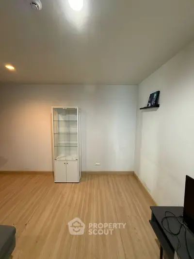 Spacious room with wooden flooring and display cabinet, ideal for modern living.