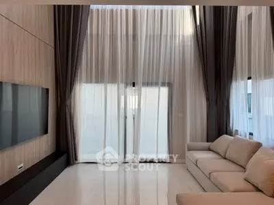 Luxurious living room with high ceilings, elegant curtains, and modern furnishings.