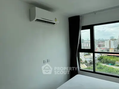 Modern bedroom with air conditioning and city view through large window.