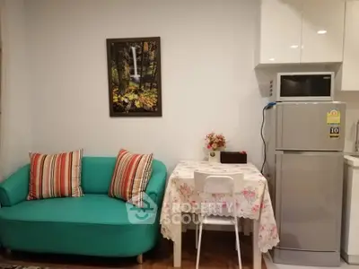 Charming compact living space with teal sofa, dining table, and modern kitchen appliances.