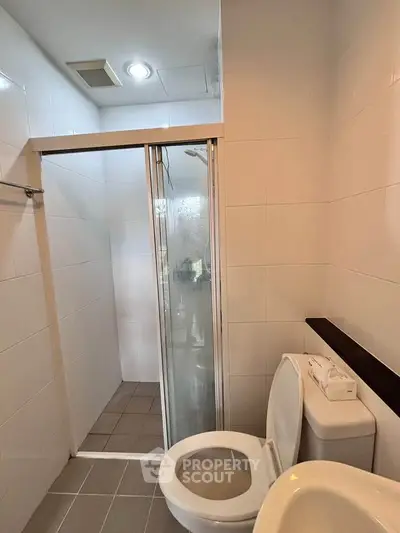Modern bathroom with glass shower door and sleek white tiles