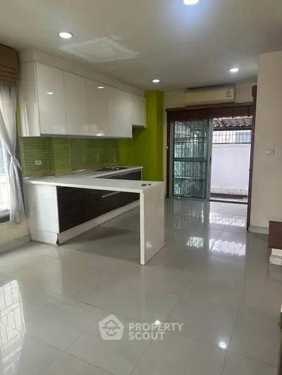 Modern kitchen with green backsplash and open layout in a bright apartment