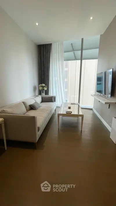 Modern living room with sleek sofa and wall-mounted TV in a high-rise apartment.