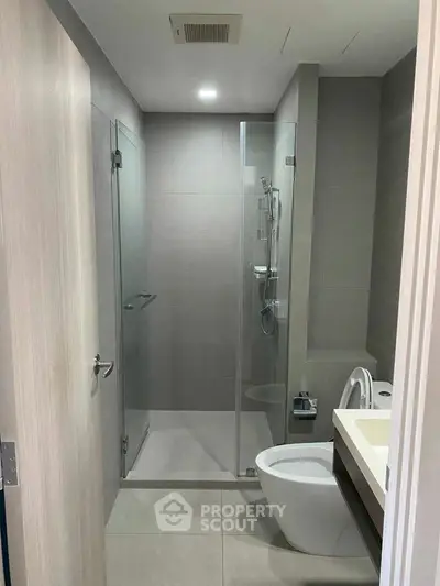 Modern bathroom with glass shower and sleek fixtures in contemporary apartment.