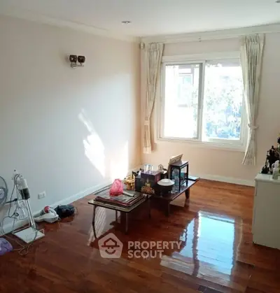 Bright living room with wooden floors and large window, minimalistic decor