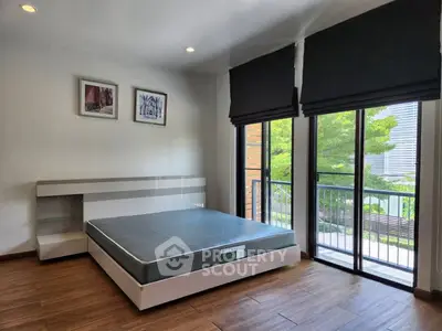 Spacious bedroom with large windows and modern decor, featuring a serene view.