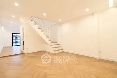 Spacious modern living room with elegant wooden flooring and stylish staircase