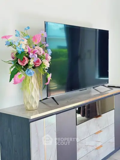 Modern living room with sleek TV stand and vibrant floral arrangement, perfect for stylish home decor.