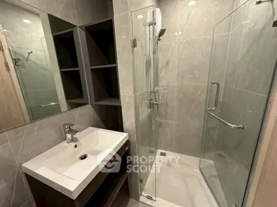 Modern bathroom with glass shower and sleek vanity in contemporary apartment.