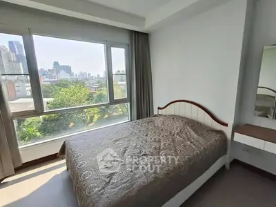 Bright bedroom with large window offering stunning city view in modern apartment.