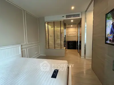 Modern bedroom with stylish decor and spacious layout, featuring a comfortable bed and elegant wall paneling.