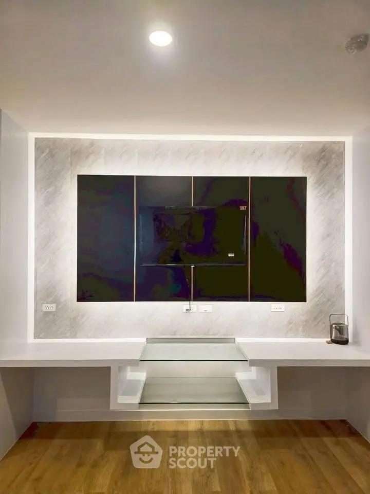 Modern minimalist living room with sleek built-in entertainment unit and wooden flooring.
