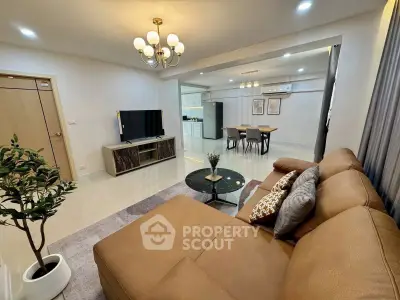 Spacious modern living room with open kitchen, elegant chandelier, and cozy seating area.