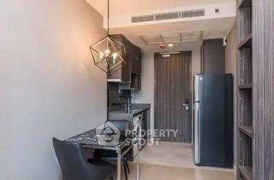 Modern kitchen with sleek design, featuring a compact dining area and stylish lighting in a contemporary apartment.