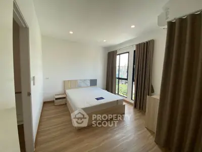 Spacious bedroom with large window and modern decor in a bright apartment.