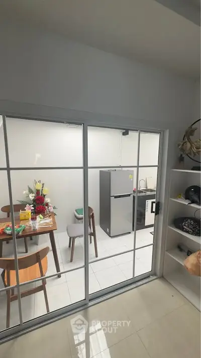 Modern kitchen with dining area and sliding glass doors, featuring a fridge and stylish decor.