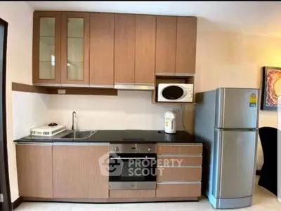 Modern kitchen with sleek cabinetry, built-in oven, and stainless steel fridge in a compact layout.