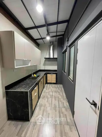 Modern kitchen with sleek black countertops and wooden cabinets in a stylish apartment.