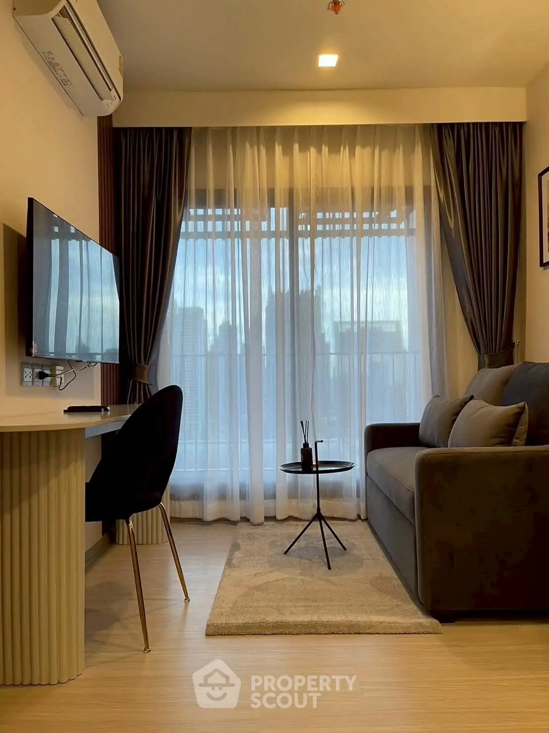 Modern living room with city view, featuring sleek furniture and large windows.