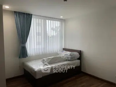 Cozy bedroom with natural light and wooden flooring, perfect for relaxation.