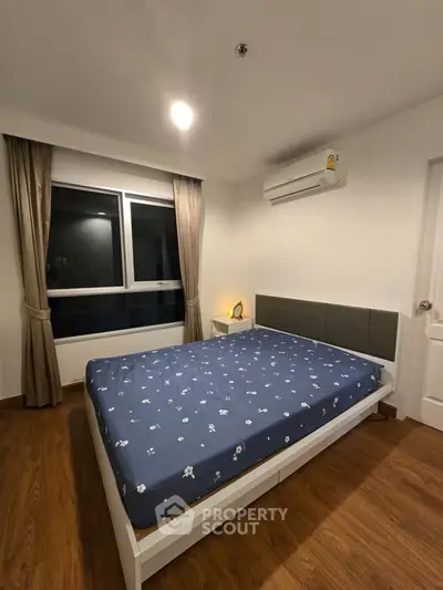 Cozy bedroom with wooden flooring and modern decor in a stylish apartment.