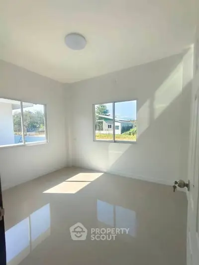 Bright and airy bedroom with large windows and glossy tiled floor, offering serene views and ample natural light.