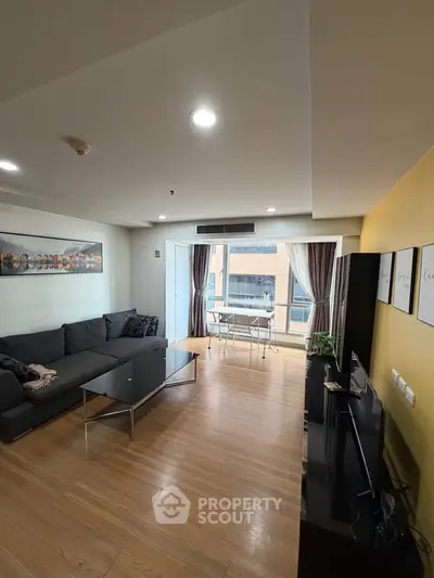 Spacious modern living room with large windows and stylish decor in a high-rise apartment.